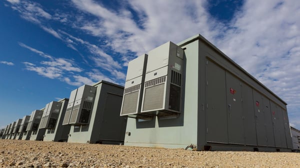 Battery storage units in a desert landscape with a blue sky