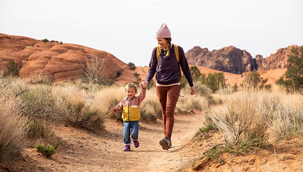 Woman walking with her child in a desert.